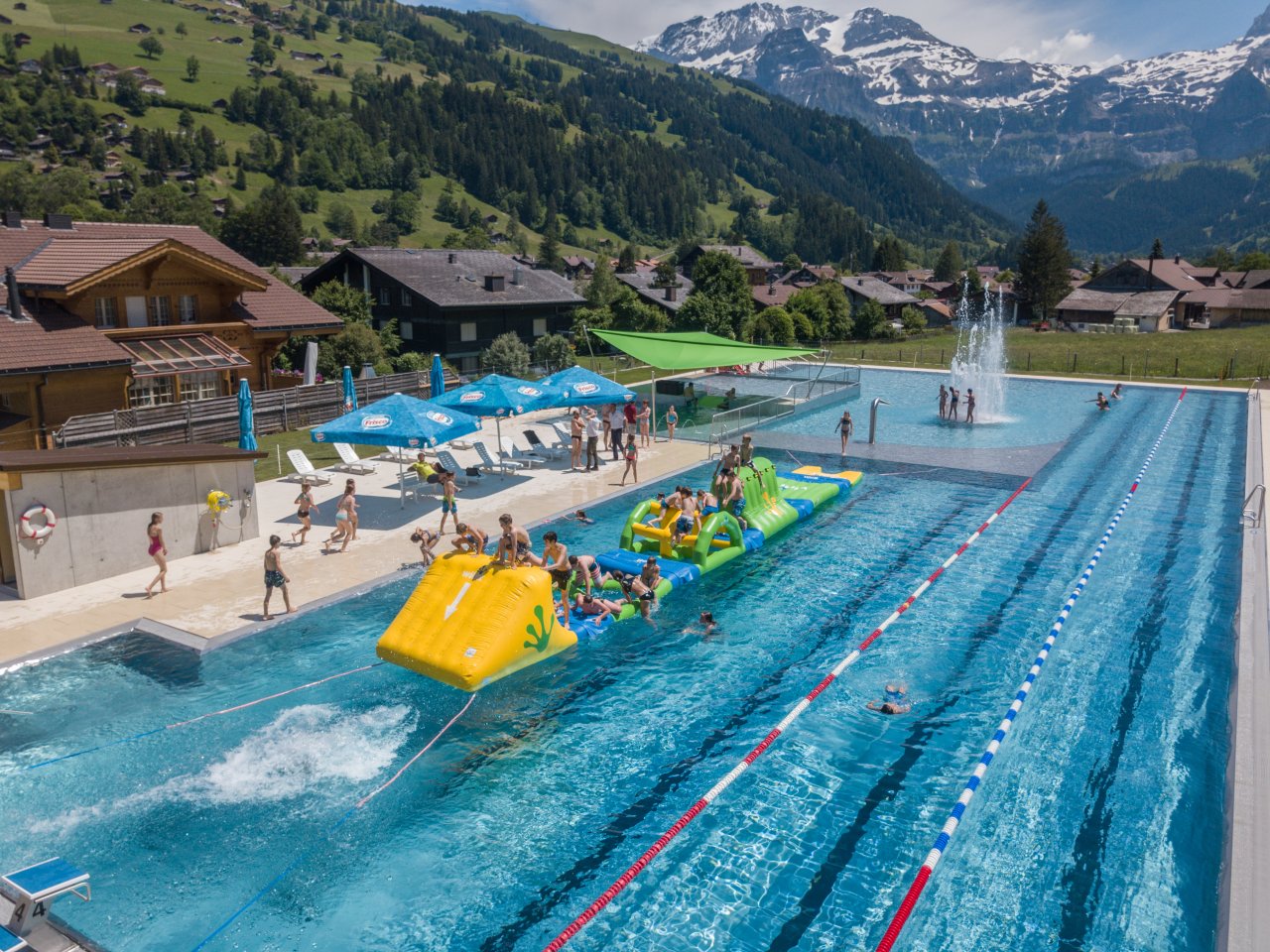 Das Lenker Freibad mit einer aufblasbaren Spielinsel und dem bewaldeten Gegenhang.